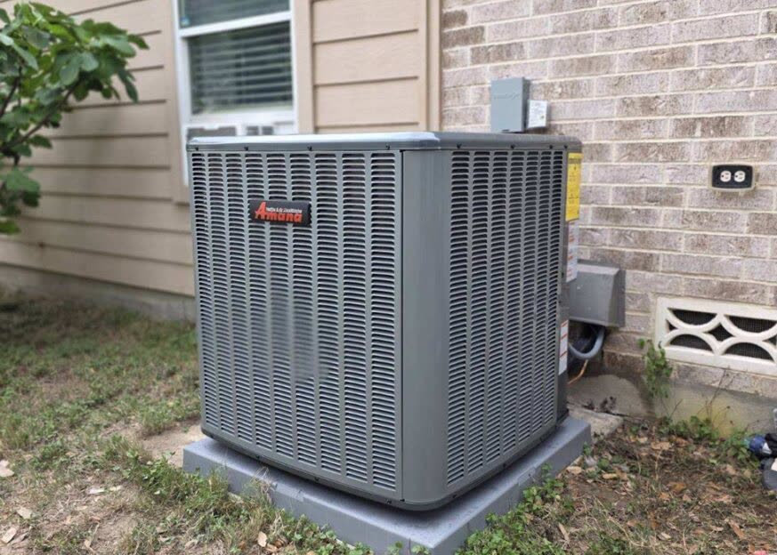 Amana condenser unit freshly installed beside a brick home